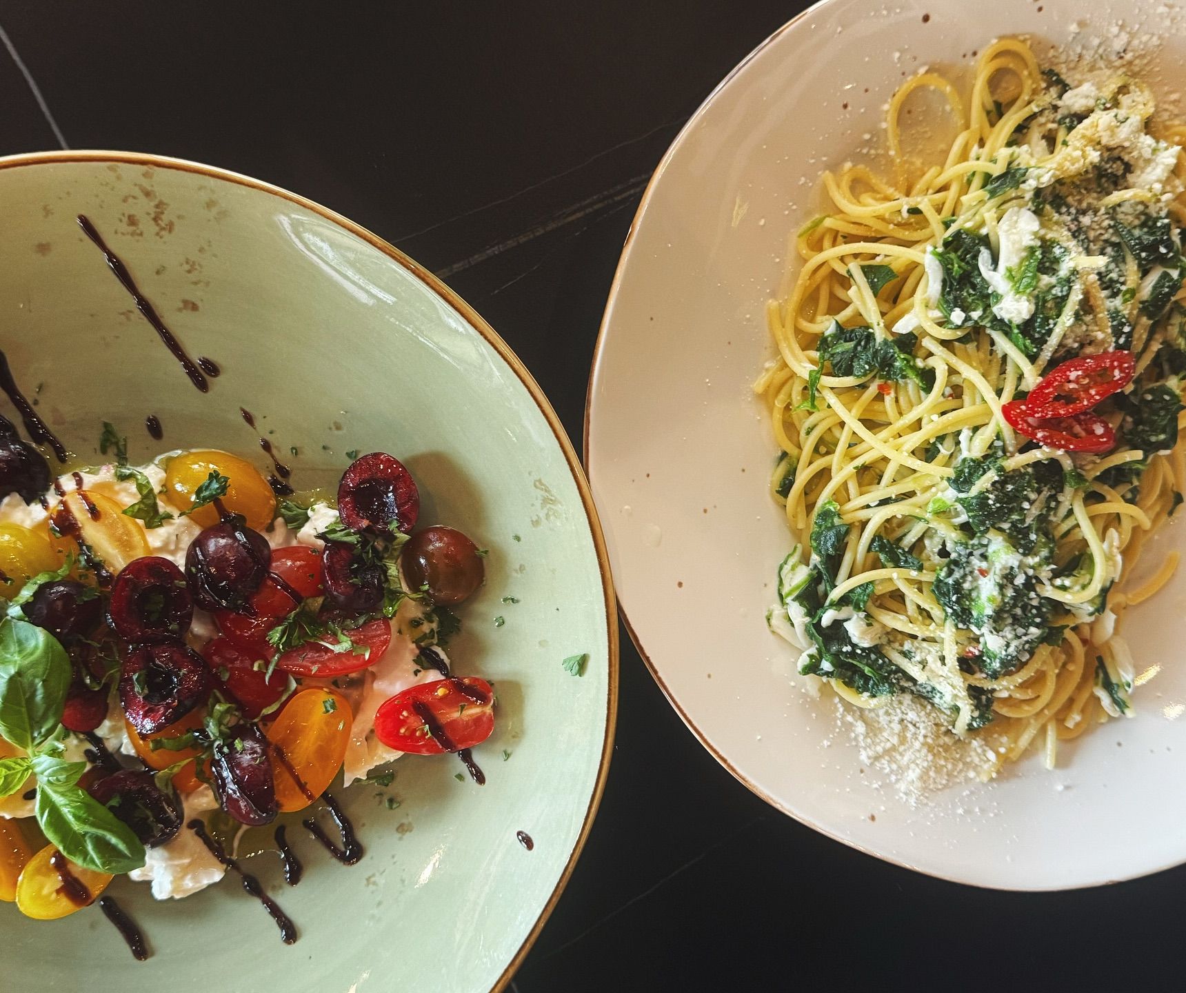 A plate of pasta and a colorful tomato-cherry salad create a fresh, vibrant lunch scene. The bright ingredients and simple plating make everything look homemade and full of flavor. It’s the kind of meal that feels light but satisfying.