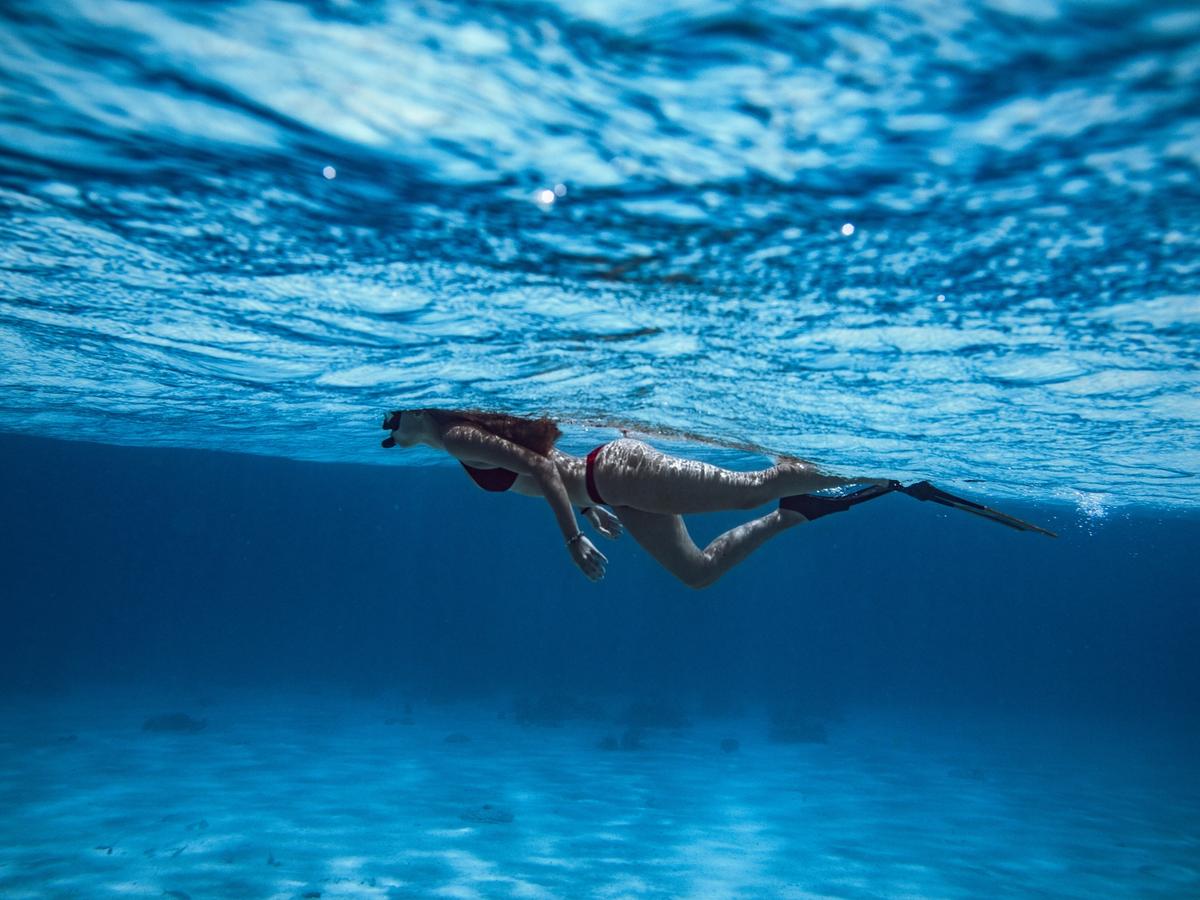 Girl underneath water with snorkeling gear on in ocean