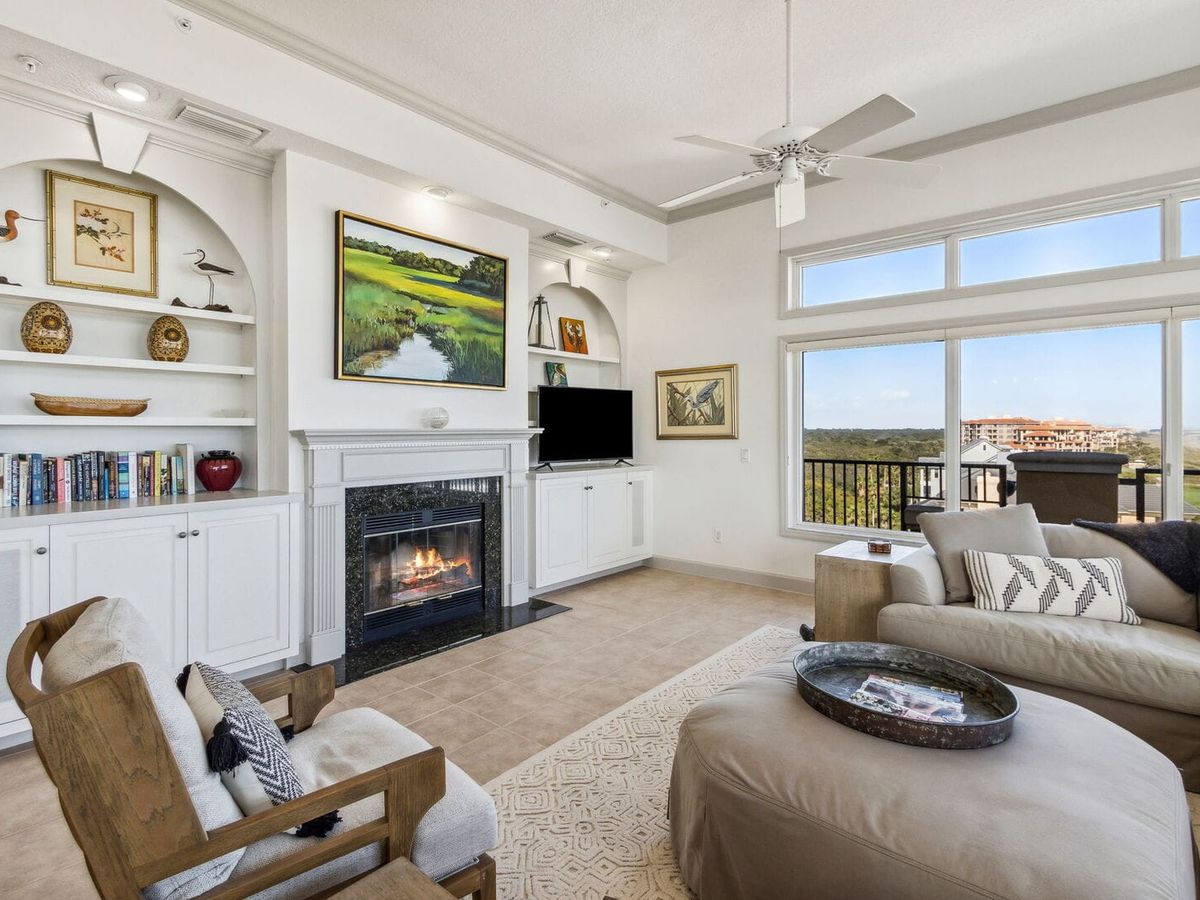 Elegant coastal living room with a fireplace, built-in bookshelves, and sweeping views of the shoreline. The perfect space for families to unwind after a day at the beach.