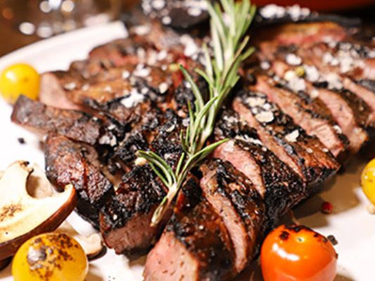 A juicy sliced steak topped with rosemary, served with grilled vegetables and tomatoes. Thoroughbreds Chophouse is a Myrtle Beach classic for fine steaks and upscale dining.