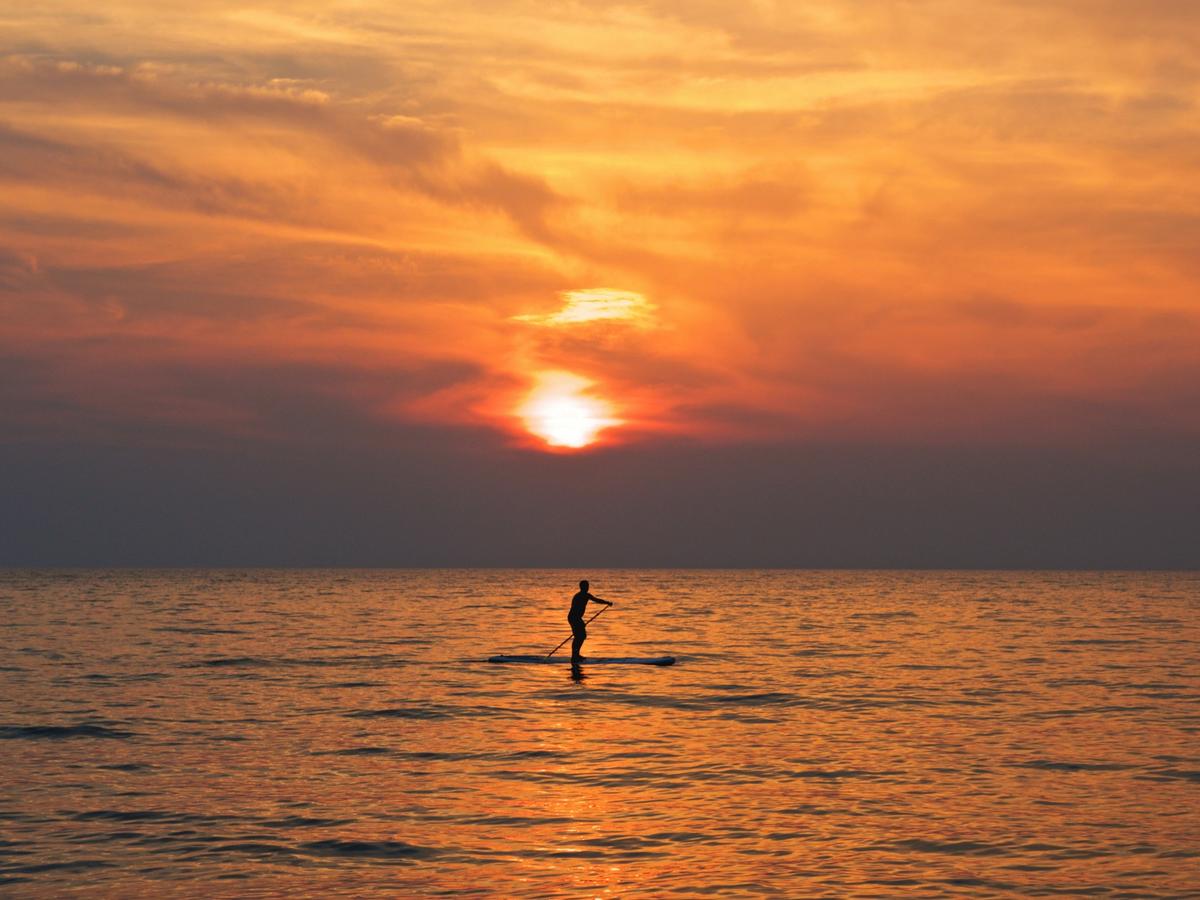 Person on paddleboard with sunset views on ocean