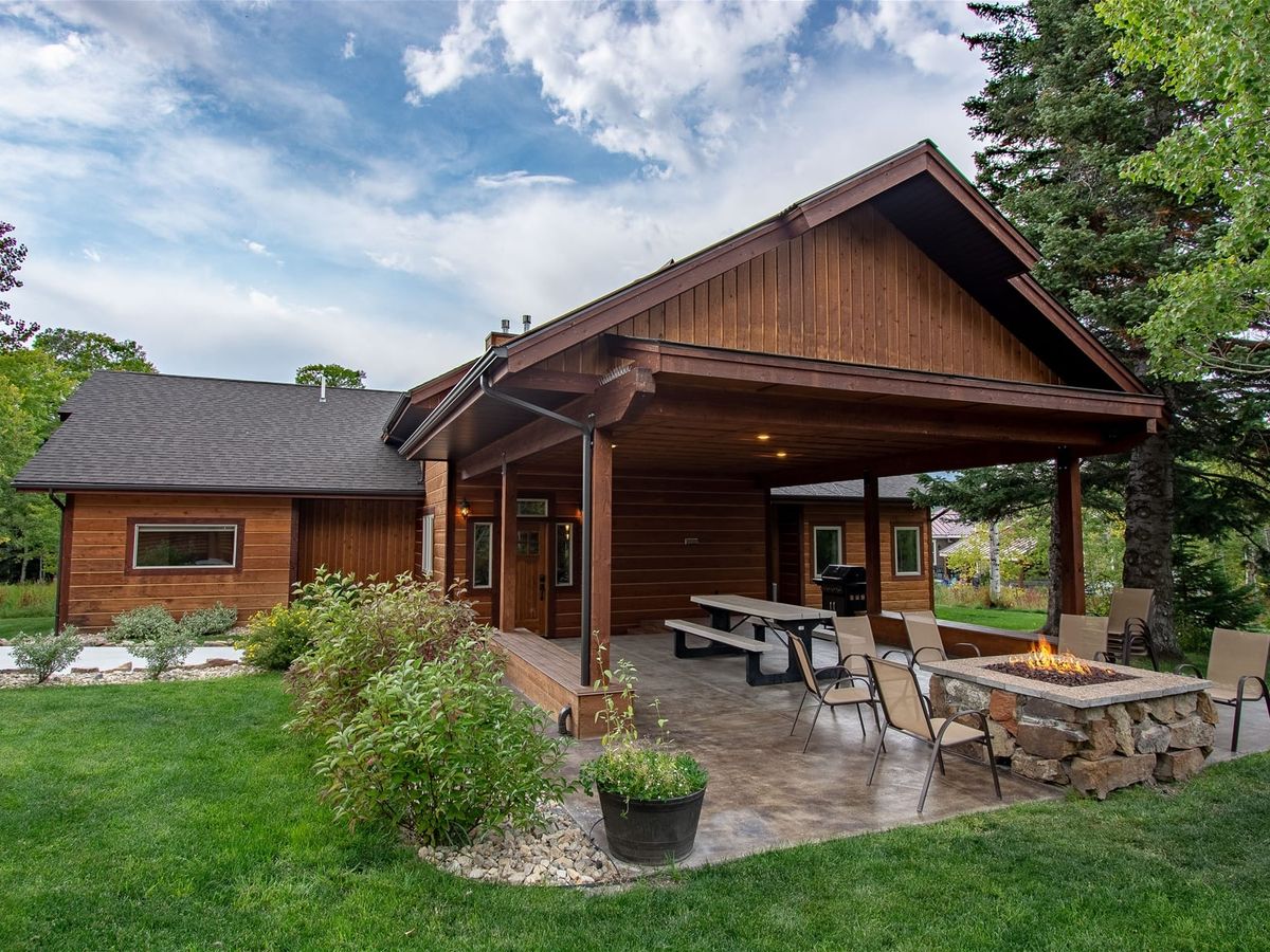 A brown lodge with outdoor dining and an outdoor firepit in West Yellowstone