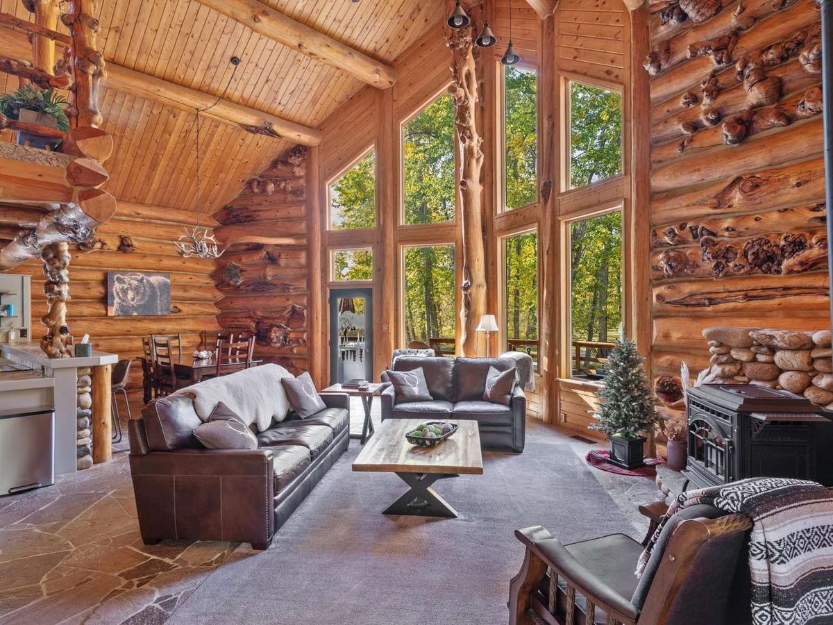 A dreamy log cabin filled with handcrafted wood details, giant windows, and cozy leather seating. The warmth of the fireplace and forest views make it feel like a fairytale tucked in the trees.