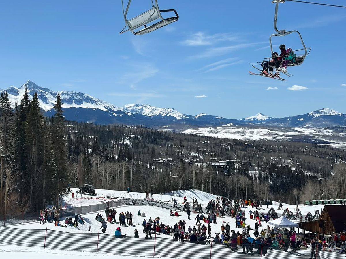 Families and skiers enjoy a sunny day at Telluride Ski Resort with snow-covered slopes, chairlifts, and panoramic mountain views in the background. One of Colorado's best ski spots for winter fun and scenic adventure.