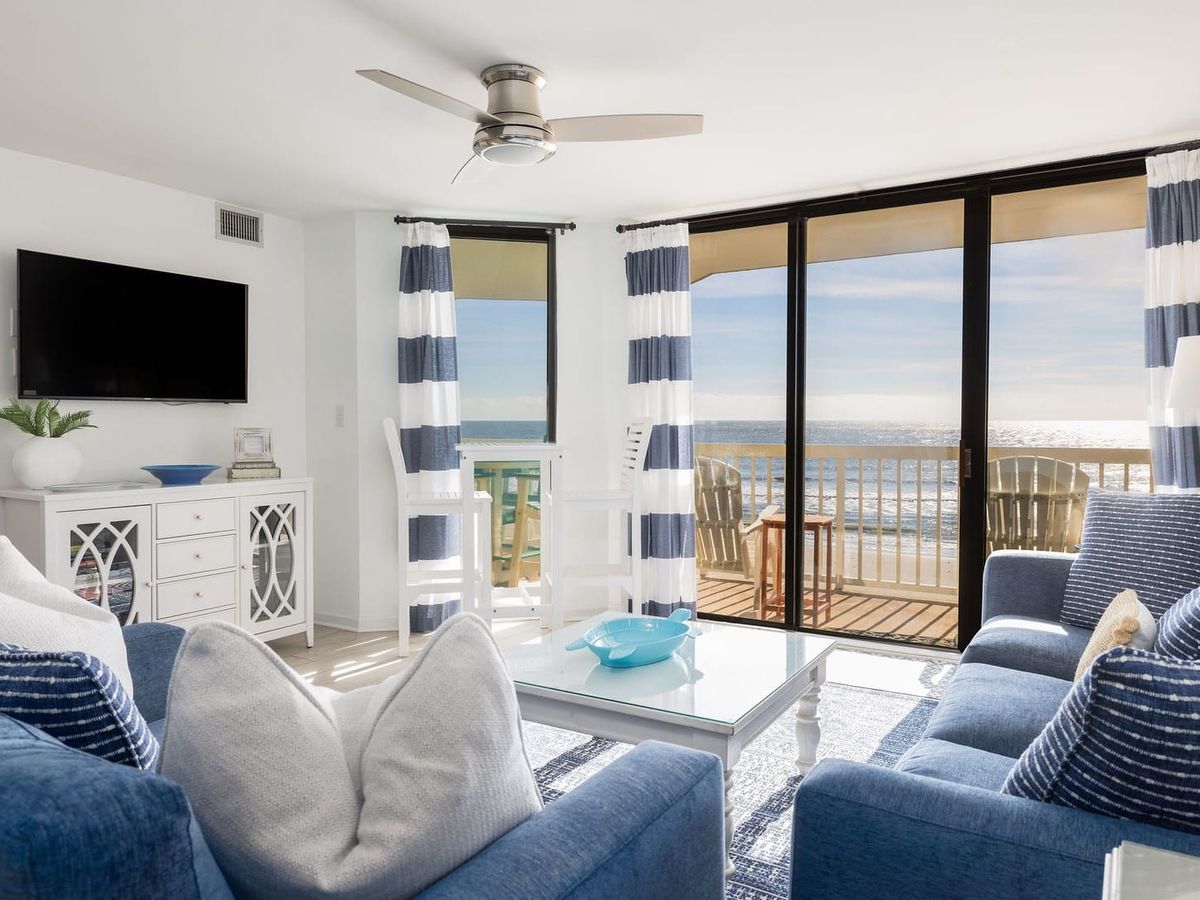 Interior living room with blue and white striped curtains and blue couches with ocean views