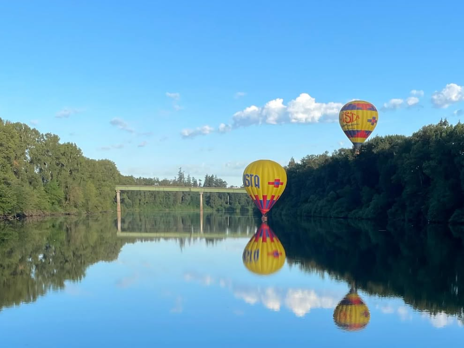Two hot air balloons side by side right by and on the lake of oregon