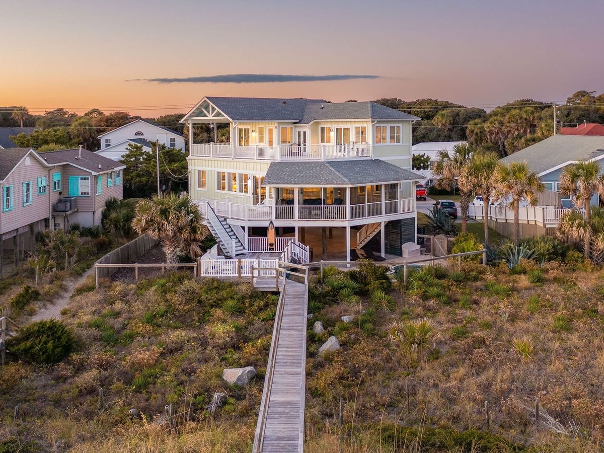 Exterior of home with boardwalk and grass surrounding the beach access