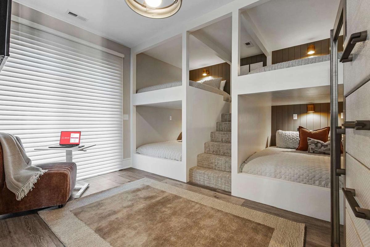 Built-in bunk beds with soft lighting create a cozy sleeping space perfect for kids or group stays. This stylish bunk room offers multiple beds and a quiet corner chair, making it ideal for large family vacation rentals.