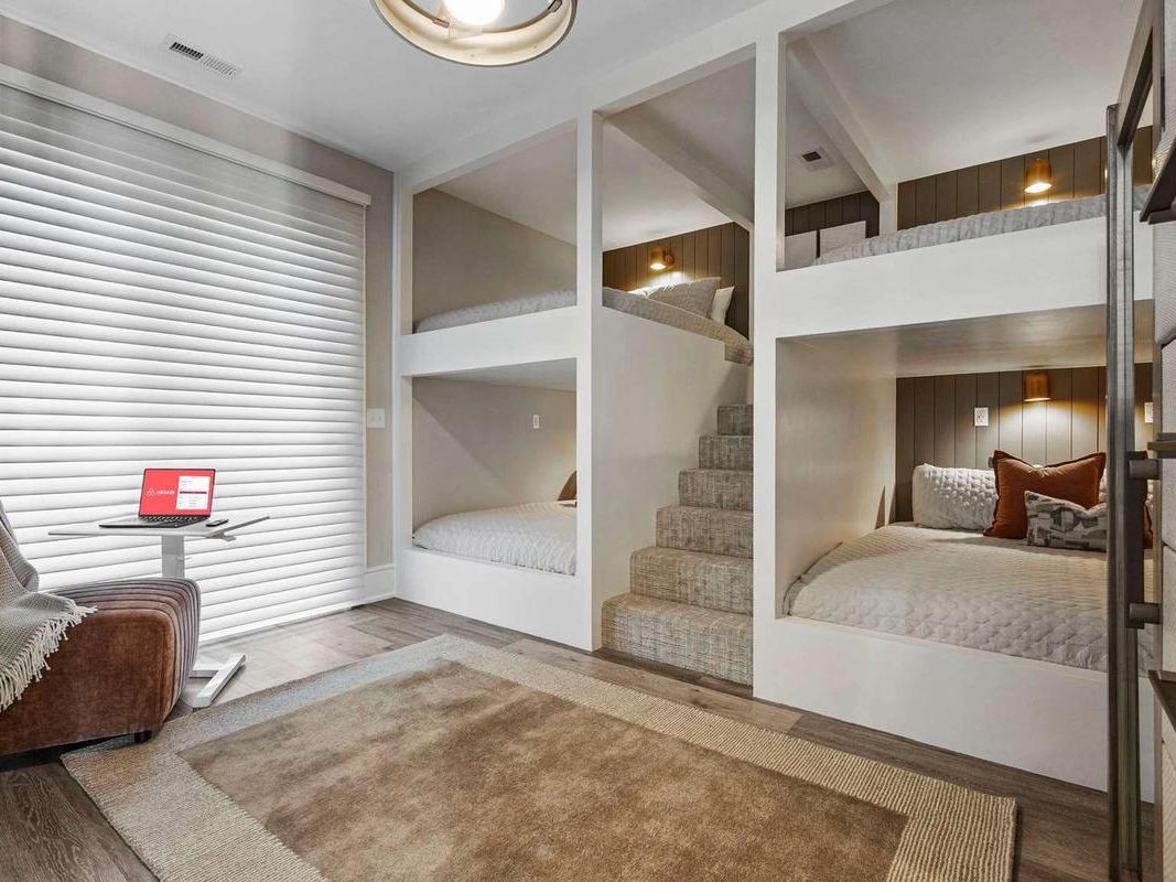 Built-in bunk beds with soft lighting create a cozy sleeping space perfect for kids or group stays. This stylish bunk room offers multiple beds and a quiet corner chair, making it ideal for large family vacation rentals.