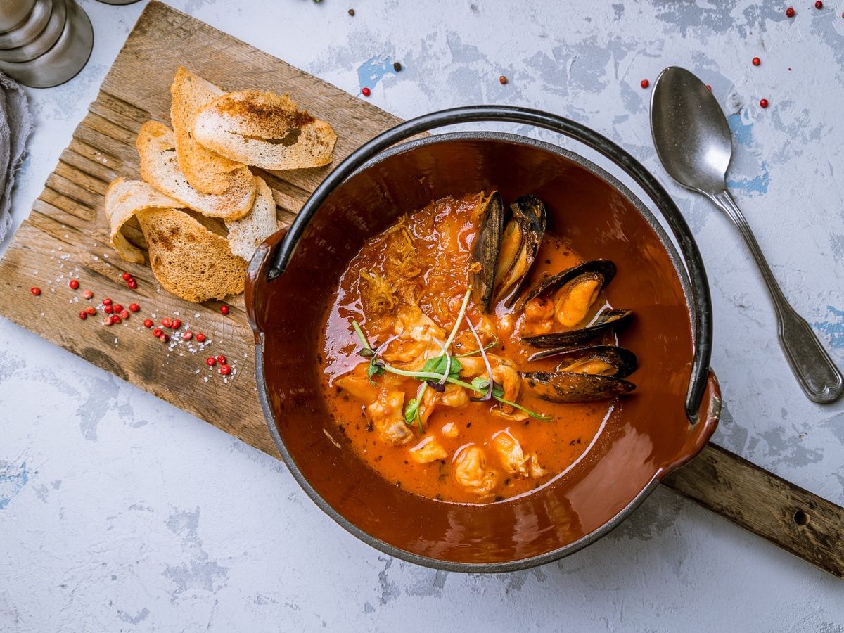 Bowl of Seafood Soup on Board With Bread
