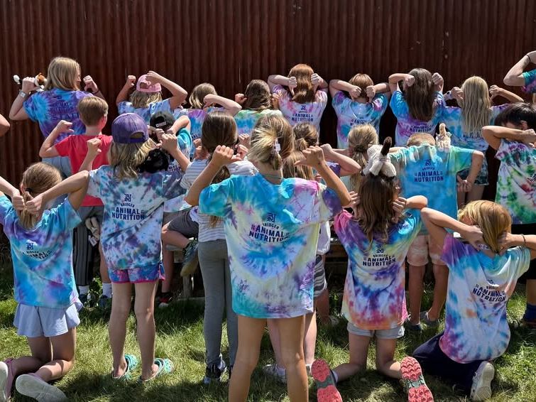 A group of children proudly show off their tie-dye shirts during the annual Snowshoe Shuffle event. Their playful poses and bright colors reflect a fun, family-friendly community gathering.