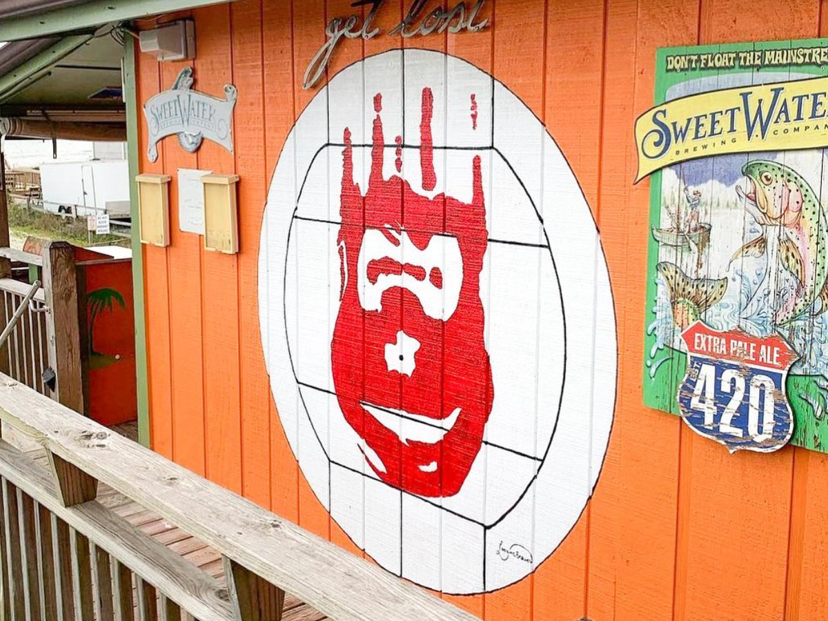 Castaway red hand paint on side of orange building in holden beach nc