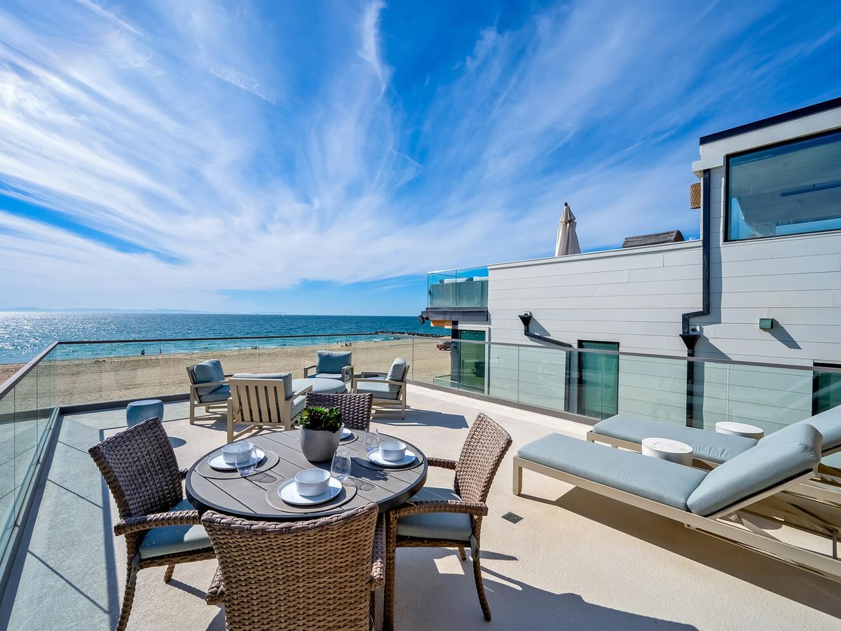Rooftop patio with dining table and lounge chairs overlooking newport beach ca