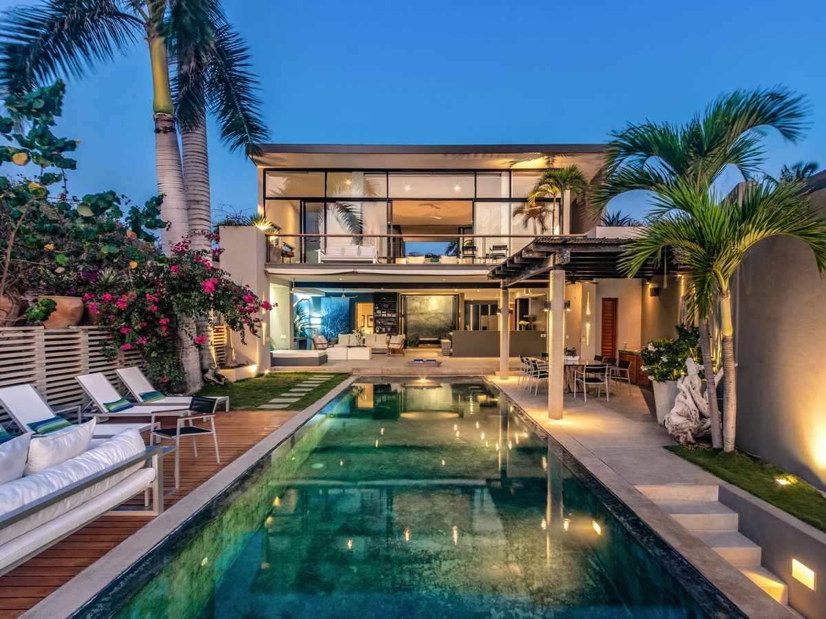 This luxury villa pairs sleek glass design with a peaceful pool surrounded by tropical plants and flowers. It’s made for laid-back afternoons and evening swims under the stars.