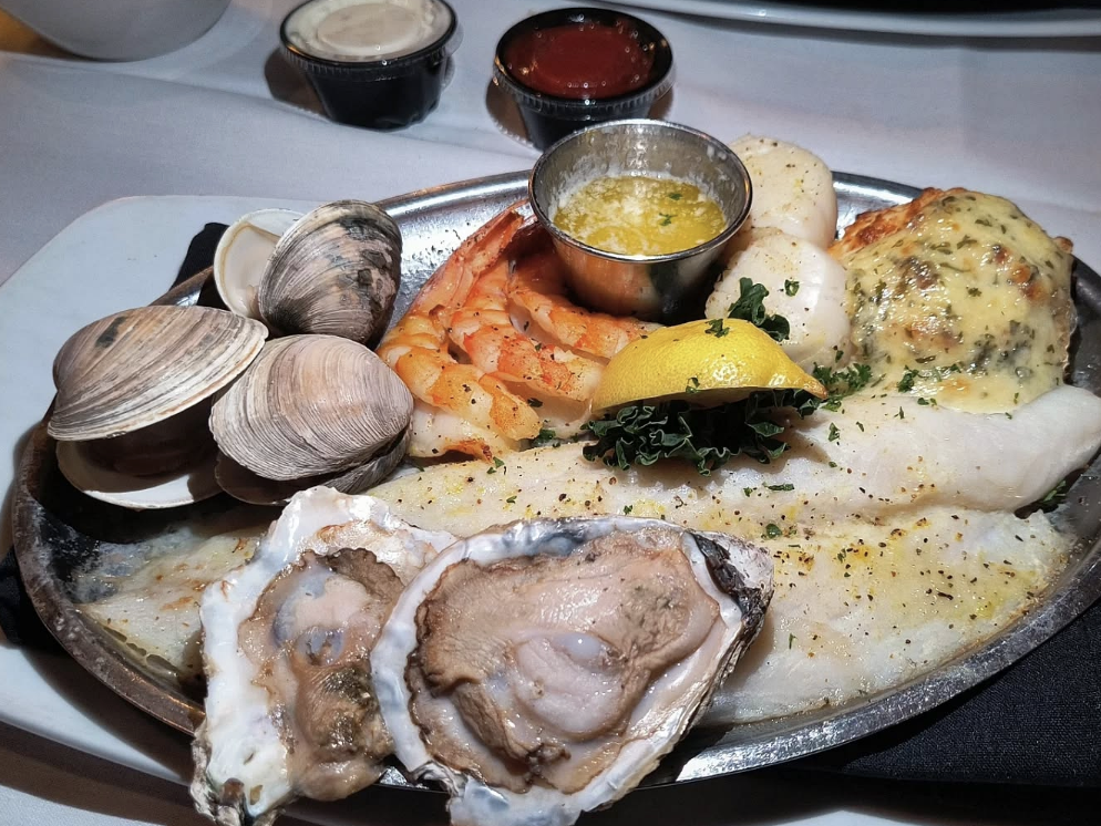 "Seafood platter at a Chincoteague Island restaurant featuring raw oysters, steamed clams, grilled shrimp, scallops, baked fish, crab-stuffed flounder, and melted butter with dipping sauces
