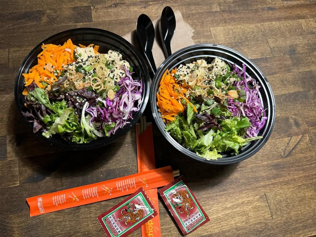 Two colorful poke bowls are filled with fresh greens, shredded carrots, purple cabbage, and tofu, topped with sesame seeds. The vibrant plant-based meal showcases Kelley Farm Kitchen’s healthy and flavorful dining style.