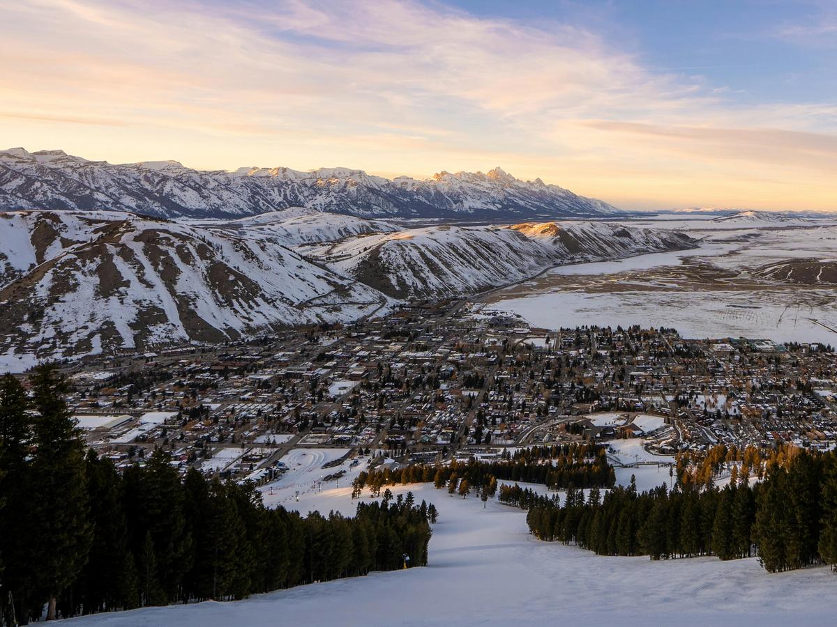 Snowy mountain tops and buildings with msun going down over the area in Jackson WY