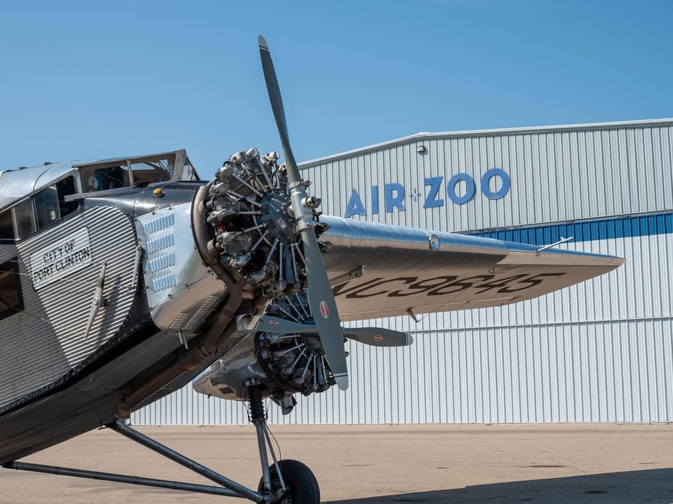 A polished vintage airplane sits proudly in front of the Air Zoo, shining under the bright blue sky. This aviation museum offers exciting exhibits, historic aircraft, and hands-on fun for the whole family