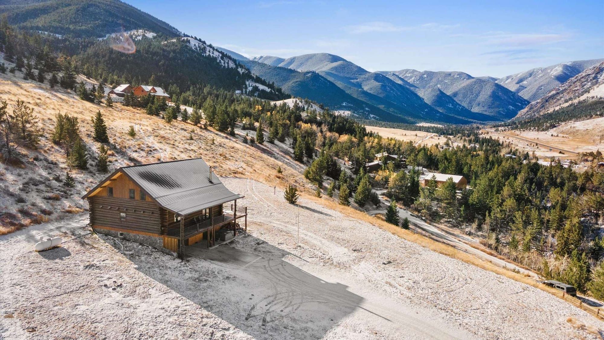 A rustic cabin in Montana surrounded by pine trees and snow-covered mountains in the distance. This peaceful escape is perfect for cozy nights by the fire and exploring the great outdoors.
