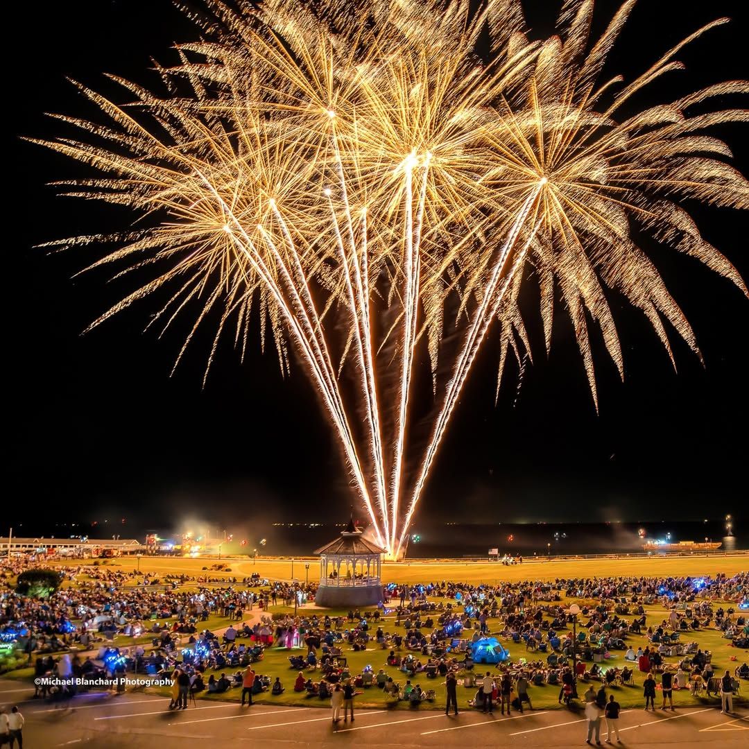 Brilliant fireworks light up the night sky over Oak Bluffs during the Martha’s Vineyard Wind Festival. Spectators fill the park below, enjoying a dazzling show that celebrates summer on the island.