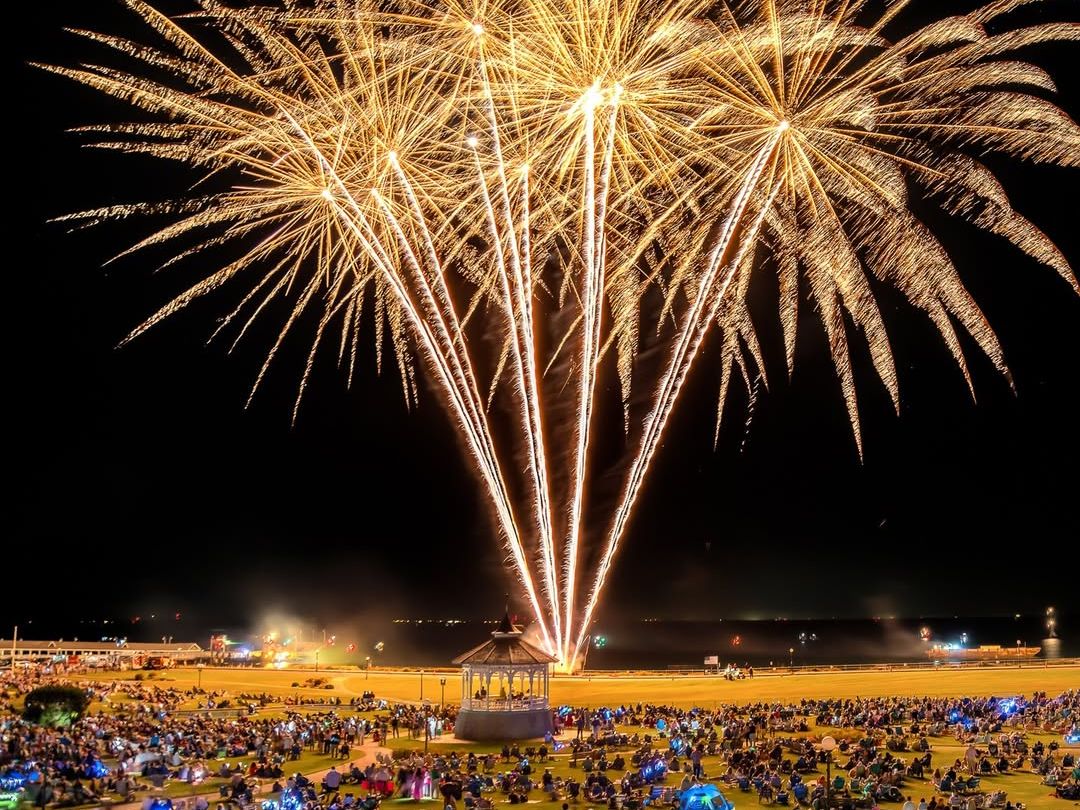 Brilliant fireworks light up the night sky over Oak Bluffs during the Martha’s Vineyard Wind Festival. Spectators fill the park below, enjoying a dazzling show that celebrates summer on the island.