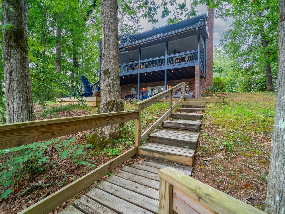Spacious outdoor living room with a stone fireplace, large sectional, and views of the trees and nearby creek. With a hot tub and pet-friendly setup, this one’s made for both family and furry friends.