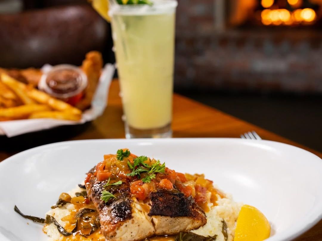 Fiddlers on Arnold dishes up blackened fish on creamy grits with braised greens and tomato relish, plus a tropical cocktail. A cozy fireside meal made for seafood lovers.