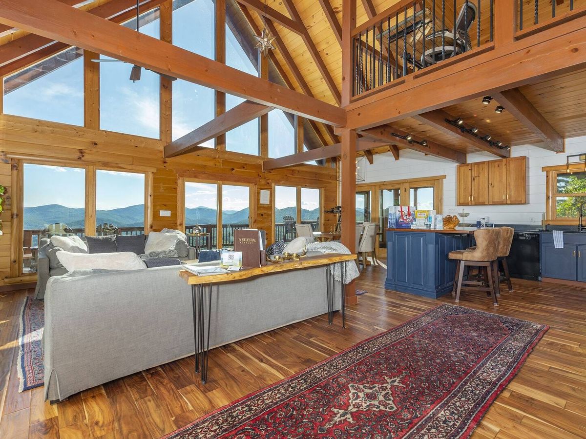 A Celestial Chalet is a warm, wood-paneled cabin in Asheville with leather couches, tall windows, and beautiful mountain views. Guests can enjoy the hot tub, fire table, and heated floors while feeling tucked into nature.