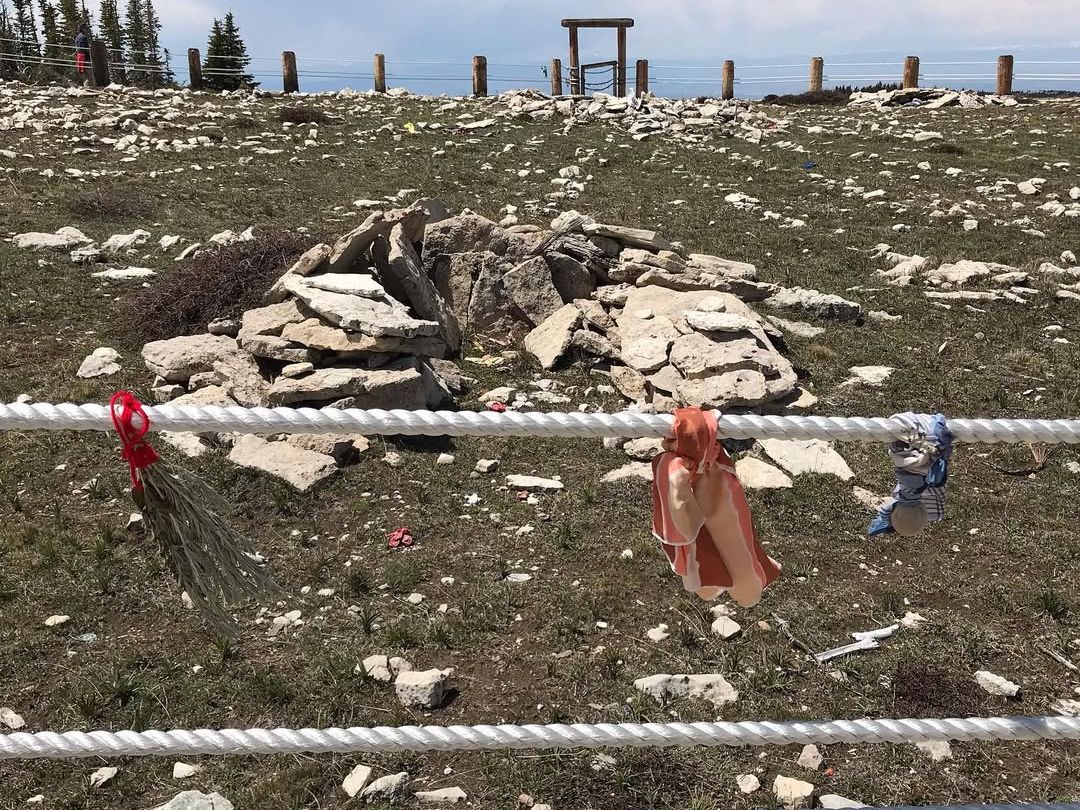 Sacred stones mark the historic Medicine Wheel Trail, a Native American cultural site high in the Bighorn Mountains. Colorful prayer ties hang along the fence, honoring ancient traditions and history.