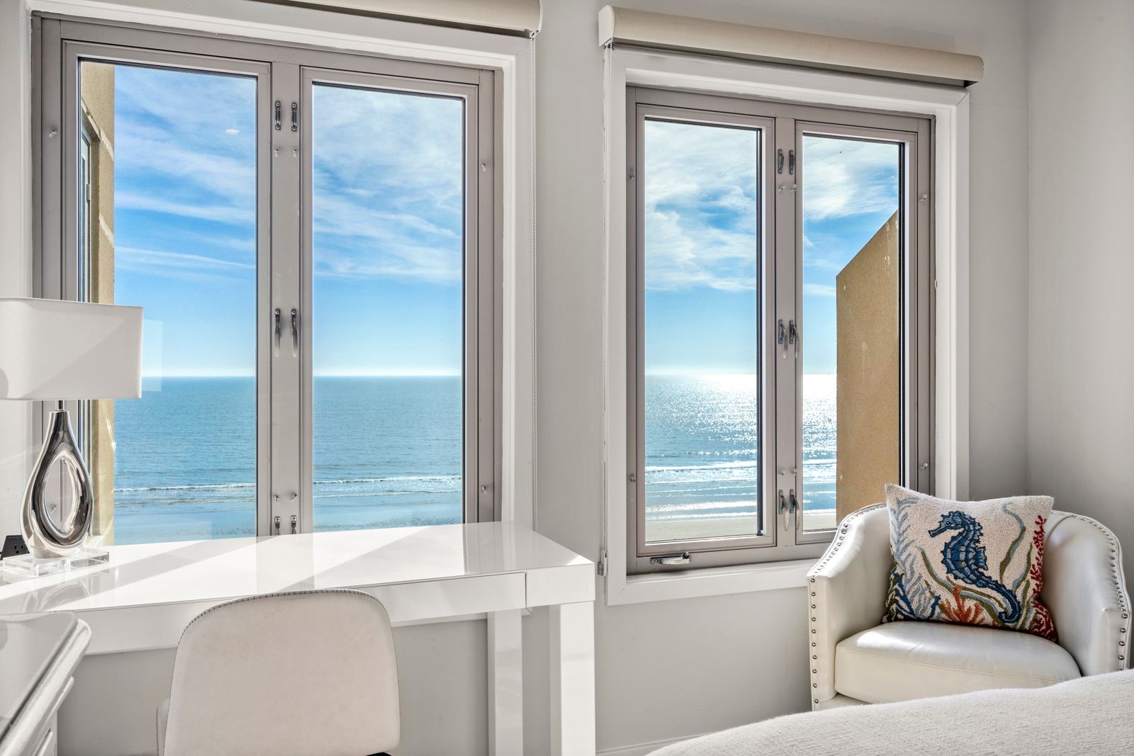 Windows in bedroom overlooking the ocean with sun shining