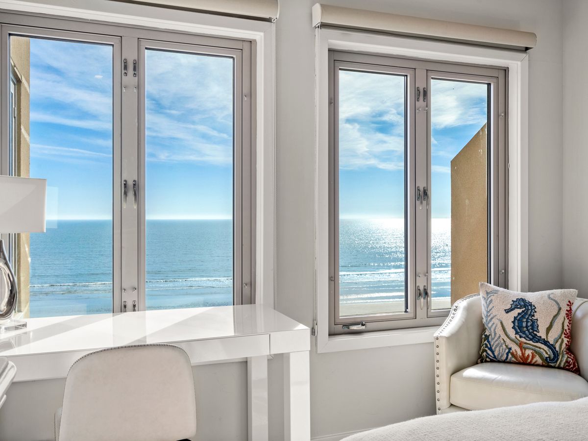 Windows in bedroom overlooking the ocean with sun shining