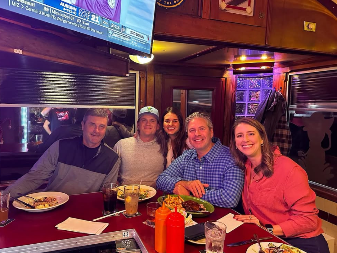 5 people side by side sitting at red bar top in restaurant