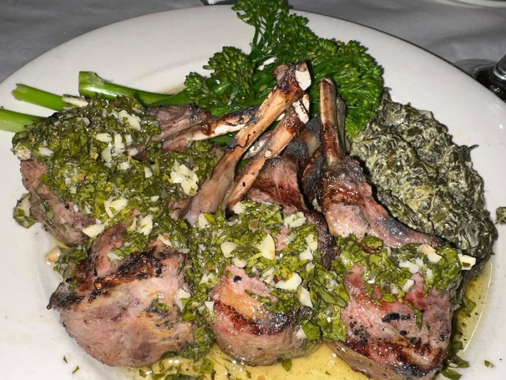 Three pork chops side by side with pesto dressing on top and near broccolini