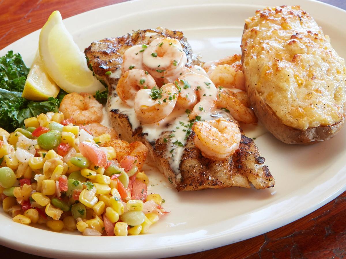 Grilled fish topped with creamy shrimp sauce, served with corn medley and a twice-baked potato. A classic Gulf Coast plate from The Back Porch in Destin.