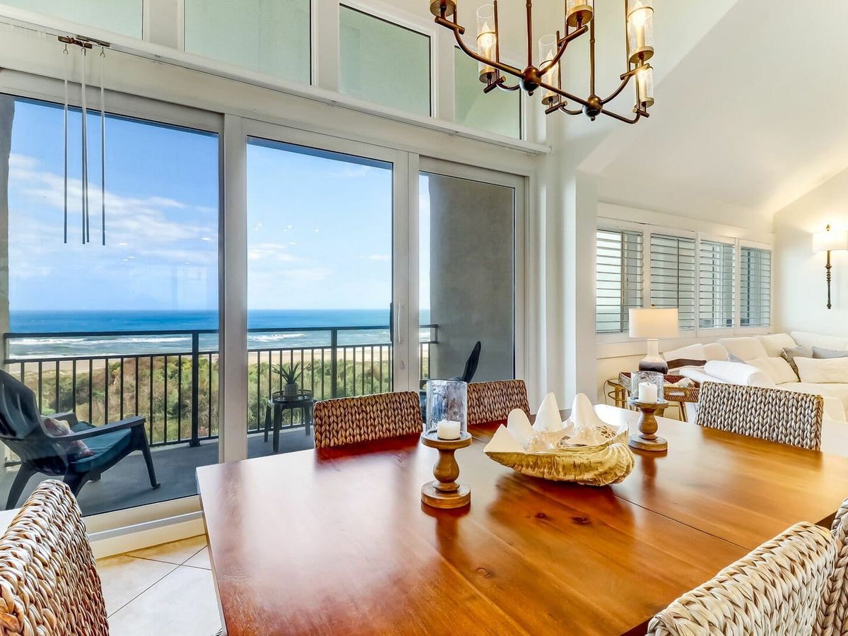 Stylish dining and living space with woven chairs, a shell centerpiece, and large windows framing ocean views. It’s the kind of place that makes dinner feel like a beachside celebration.