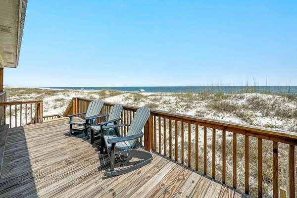 A wooden deck sits right above the dunes, with Adirondack chairs facing the blue Gulf waters. It’s a quiet and peaceful place to enjoy the breeze and watch the waves. The open sky makes the whole space feel endless.