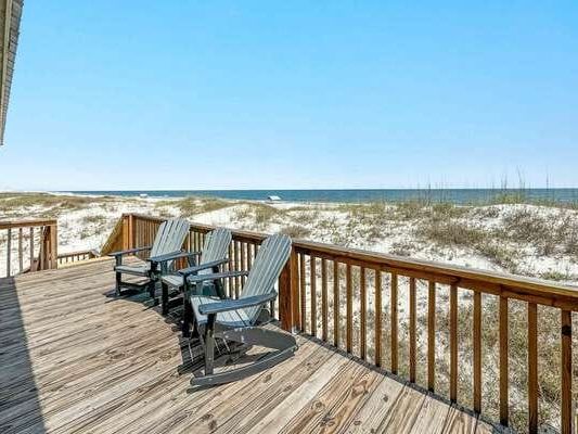 A wooden deck sits right above the dunes, with Adirondack chairs facing the blue Gulf waters. It’s a quiet and peaceful place to enjoy the breeze and watch the waves. The open sky makes the whole space feel endless.
