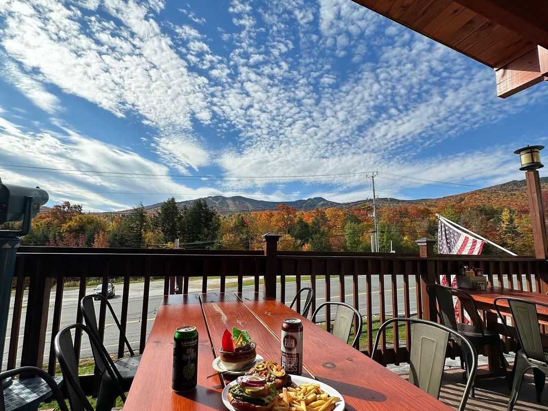 Outdoor dining at The Lookout Tavern with wooden tables, mountain views, and a relaxed Killington vibe.