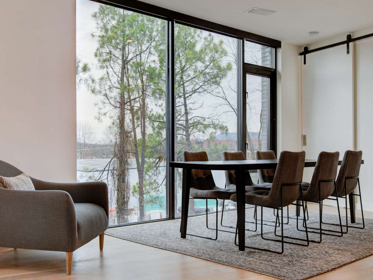 A bright, modern condo living room featuring large windows, mid-century seating, and stylish décor. With a mix of cozy and contemporary touches, this space is perfect for relaxing or entertaining in the heart of town.
