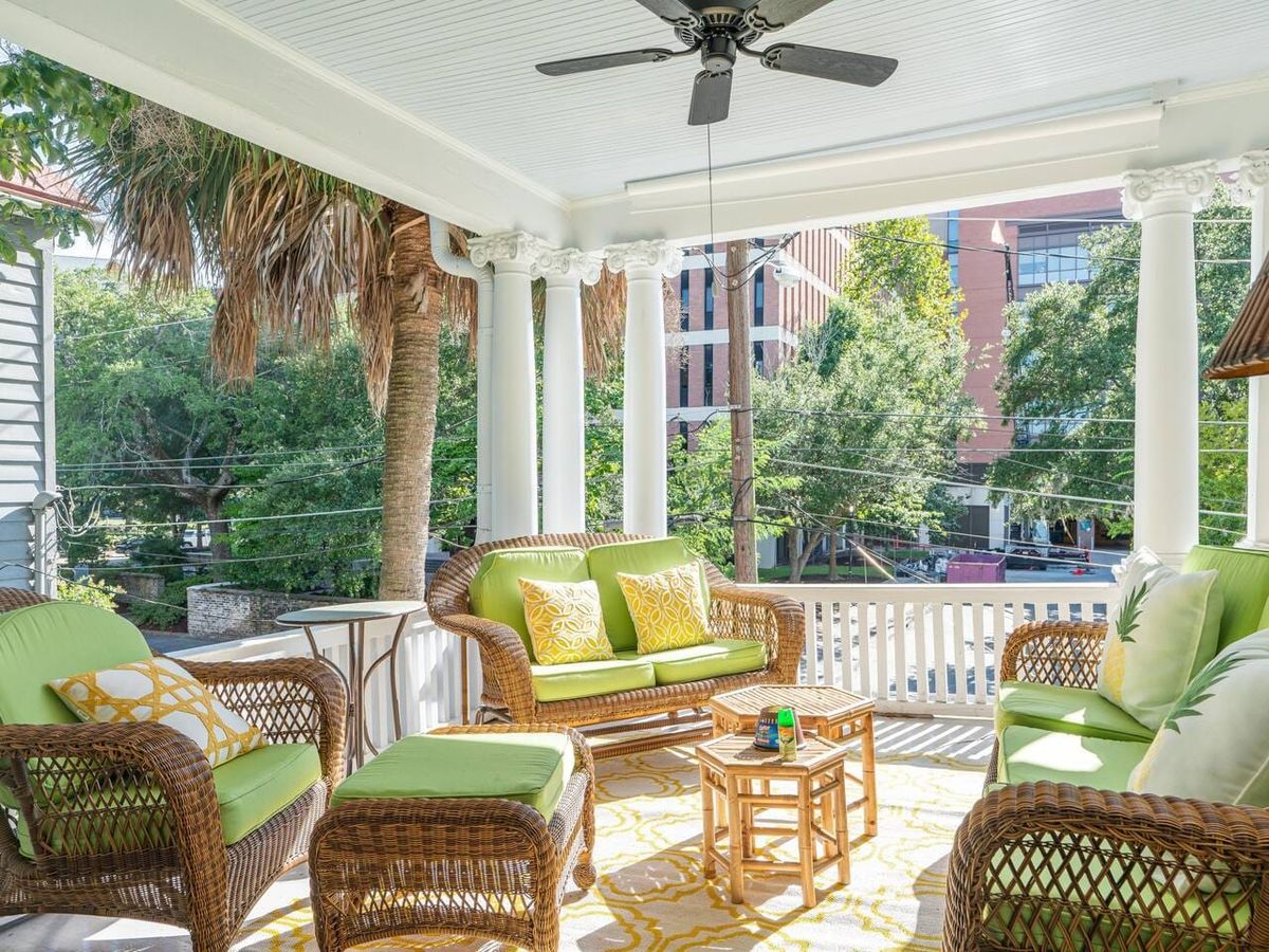 Bright and breezy porch with wicker furniture, lime green cushions, and tropical palm views. A relaxing Southern spot for morning coffee or evening chats.