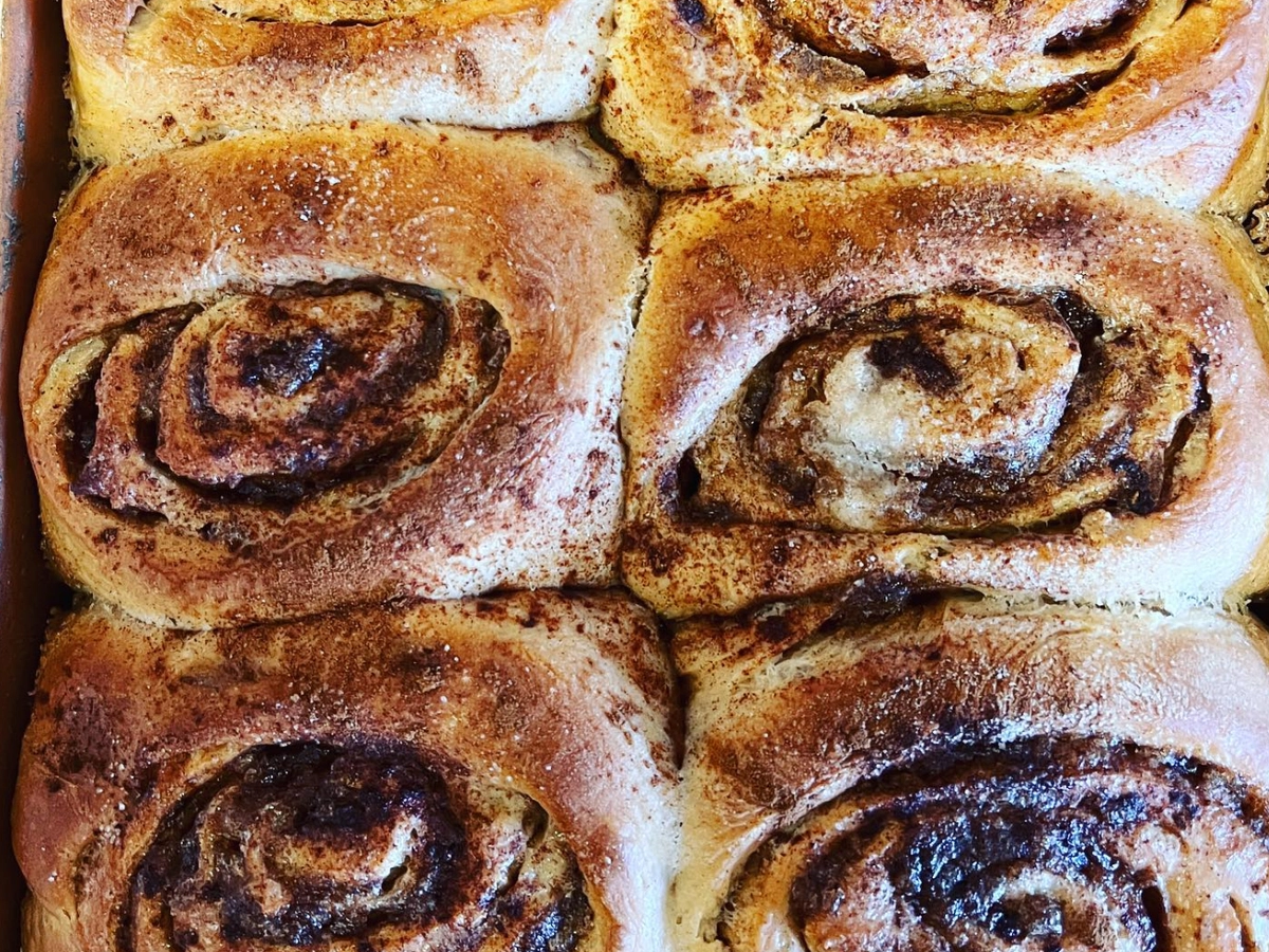 Close-up of freshly baked cinnamon rolls with golden-brown swirls of cinnamon sugar.