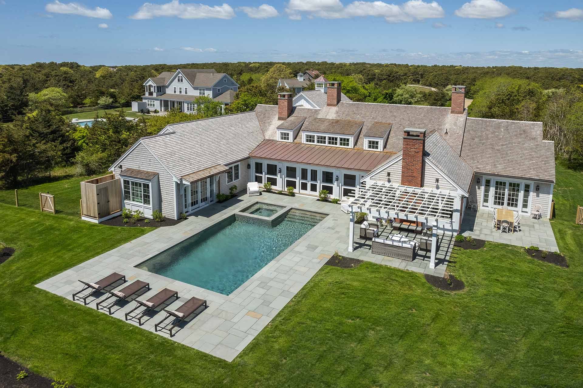 A Martha’s Vineyard luxury estate with a private pool, stone patio, and outdoor lounge surrounded by open greenery. Perfect for summer gatherings, it offers peace, privacy, and timeless coastal charm.
