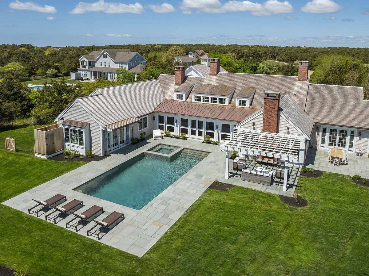A Martha’s Vineyard luxury estate with a private pool, stone patio, and outdoor lounge surrounded by open greenery. Perfect for summer gatherings, it offers peace, privacy, and timeless coastal charm.