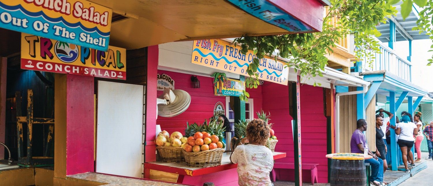 Colorful local food stalls in The Bahamas serving fresh conch salad, tropical fruit, and seafood favorites. This lively street scene shows where locals and visitors go to taste authentic Bahamian flavors. A must-see stop for food lovers exploring island cuisine.