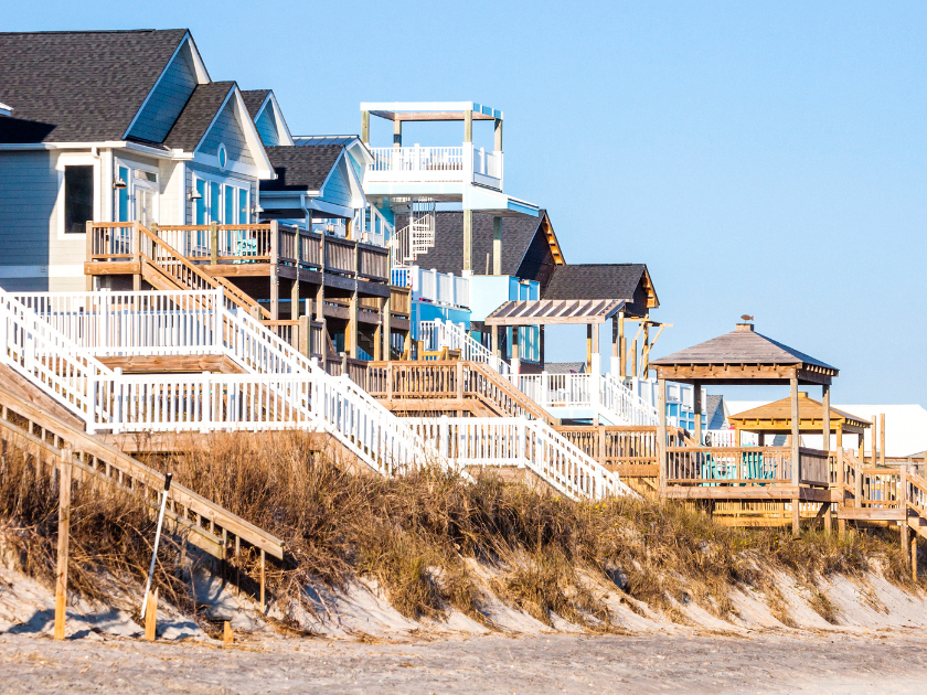 Colorful beach houses line the dunes in Surf City, all with big porches and ocean views. These homes are perfect for a relaxing coastal escape in North Carolina.