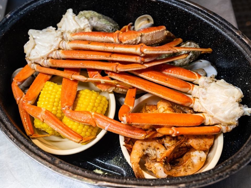 A seafood platter filled with snow crab legs, shrimp, corn on the cob, and clams served in a black dish. This classic low-country boil at Bimini’s Oyster Bar is a must-try for seafood lovers in Myrtle Beach.