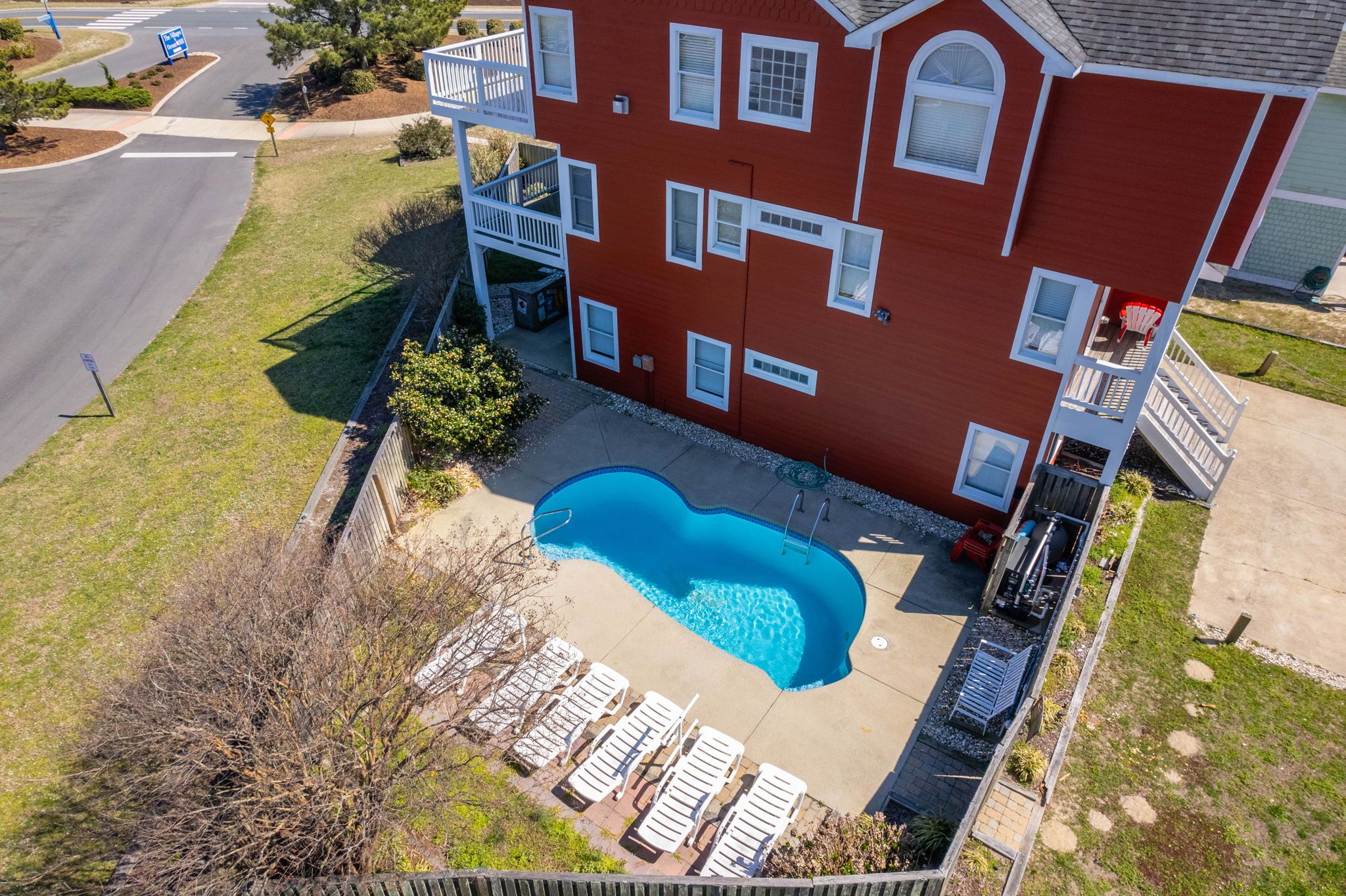 Private pool with white lounge chairs at private red home in outer banks