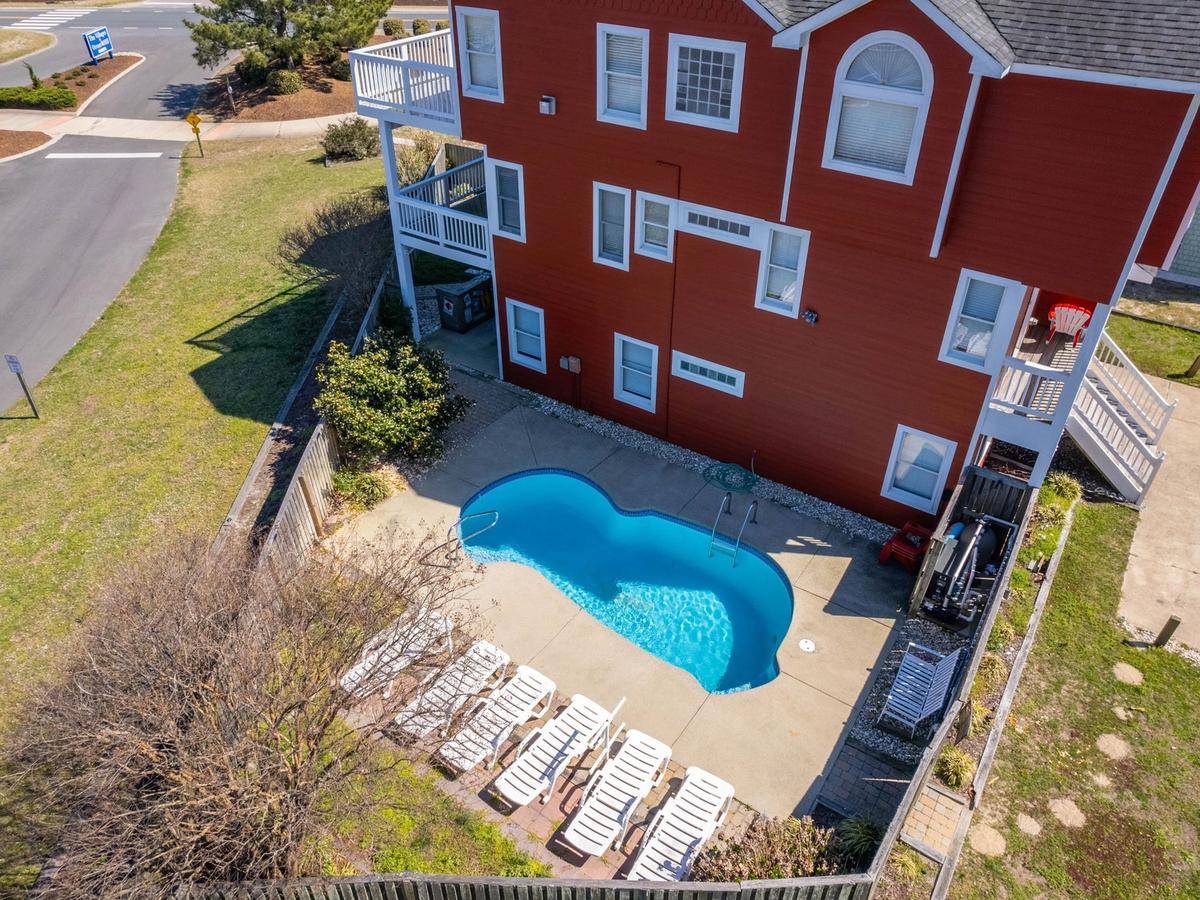Private pool with white lounge chairs at private red home in outer banks