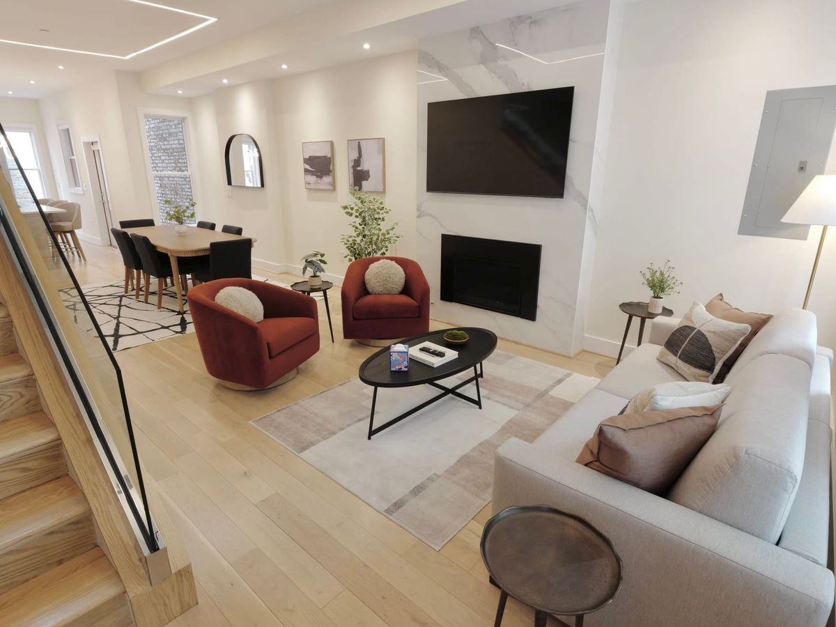 Interior of living room with two accent chairs with throw pillows on them, TV, and cozy fireplace
