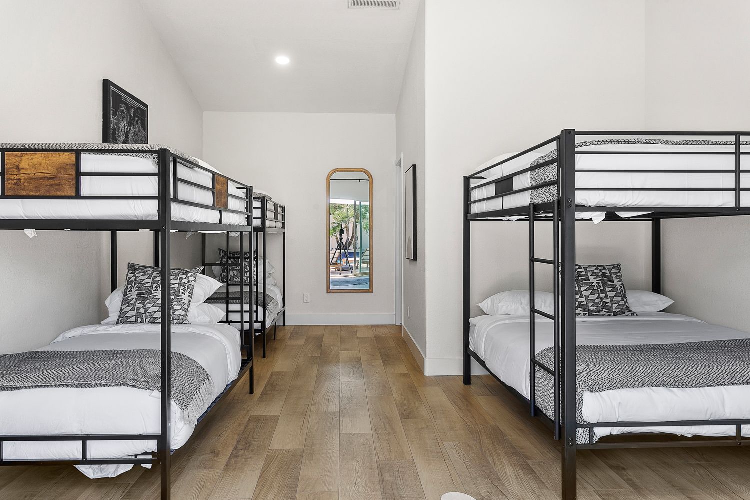 A stylish bunk room featuring multiple full-over-full beds with modern metal frames, offering a comfortable and thoughtfully designed space perfect for groups or families.